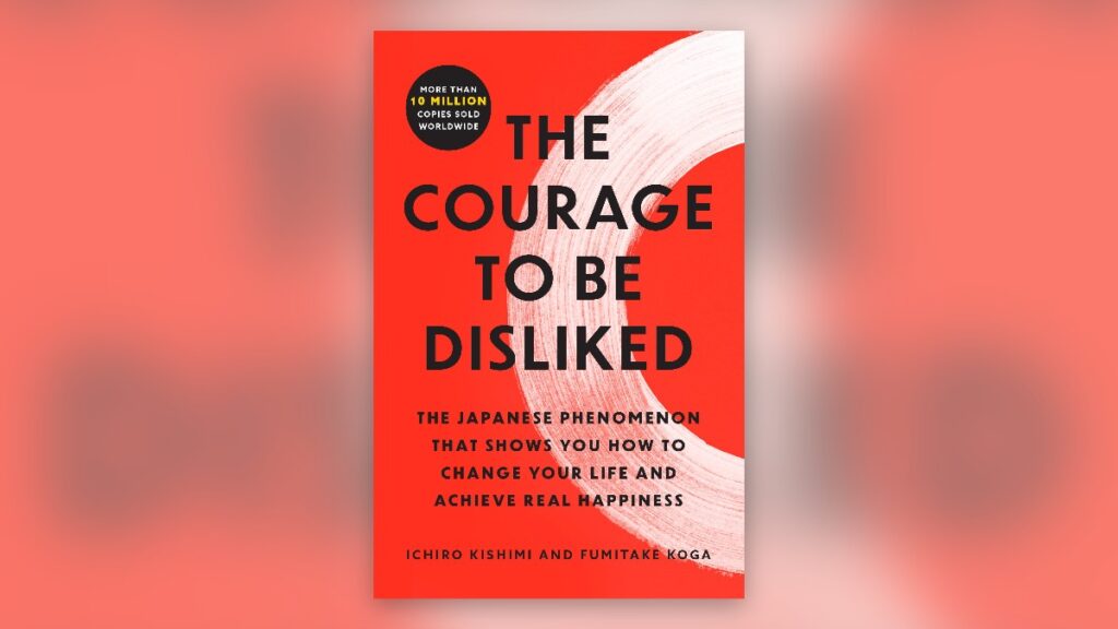 The Courage to Be Disliked by Ichiro Kishimi and Fumitake Koga, the white cover with a red brush circle, set on a blurred tint of the same cover