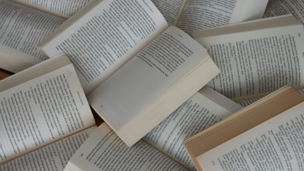 A pile of open paperback books with pages showing