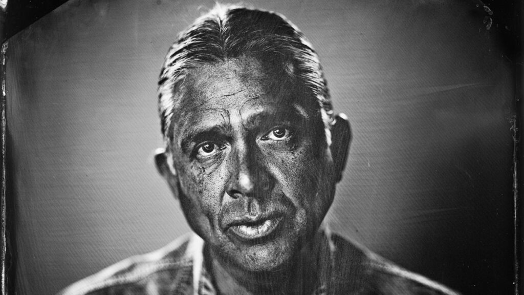 Black and white portrait of horror author Stephen Graham Jones looking straight at the camera
